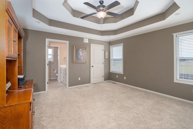 bedroom featuring connected bathroom, a raised ceiling, and multiple windows