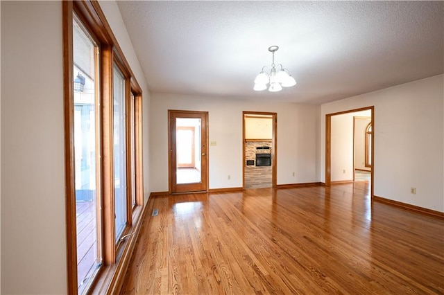 unfurnished room with a notable chandelier, a textured ceiling, and light hardwood / wood-style flooring