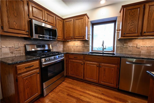 kitchen with backsplash, wood-type flooring, sink, and appliances with stainless steel finishes