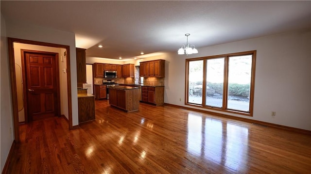 22812 E Bradford Ln, Blue Springs, MO 64015 - kitchen featuring a chandelier, stainless steel appliances, decorative backsplash, a center island, and dark wood-style flooring
