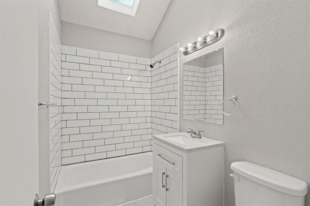 full bathroom with vanity, toilet, tiled shower / bath, and lofted ceiling with skylight