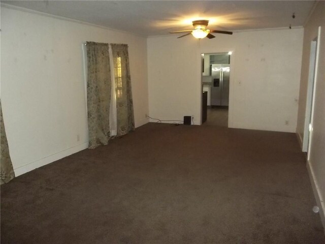 spare room featuring crown molding, ceiling fan, and dark colored carpet