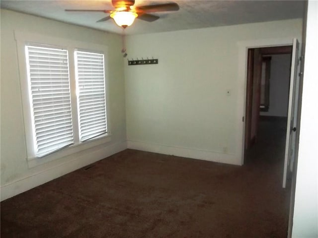 empty room featuring dark colored carpet and ceiling fan