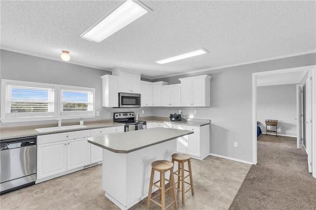 kitchen with white cabinets, sink, a kitchen island, and appliances with stainless steel finishes