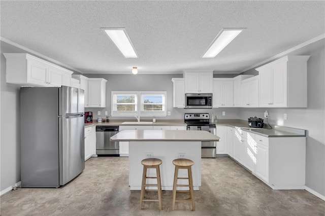 kitchen with a center island, white cabinets, a kitchen breakfast bar, a textured ceiling, and appliances with stainless steel finishes