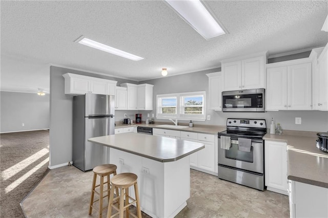 kitchen with white cabinetry, a center island, a textured ceiling, and appliances with stainless steel finishes