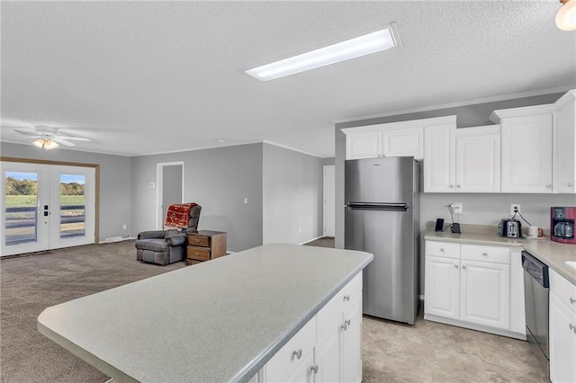 kitchen with light carpet, french doors, white cabinets, a textured ceiling, and stainless steel appliances