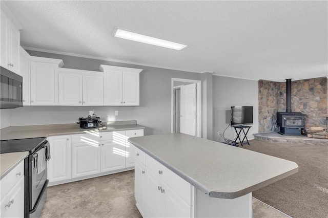 kitchen with light carpet, black range with electric stovetop, white cabinets, a center island, and a wood stove