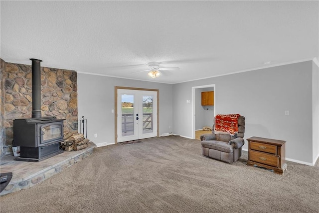 living area with carpet floors, a wood stove, ceiling fan, and ornamental molding