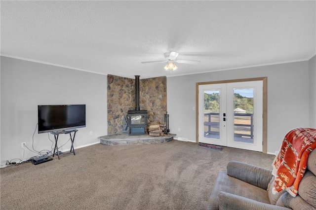 living room with french doors, carpet floors, a wood stove, and ceiling fan