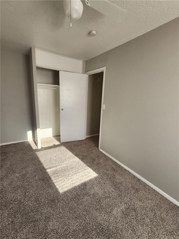 unfurnished bedroom with a textured ceiling, carpet floors, a closet, and ceiling fan