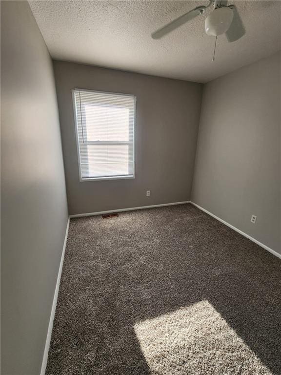 spare room with dark colored carpet, a textured ceiling, and ceiling fan