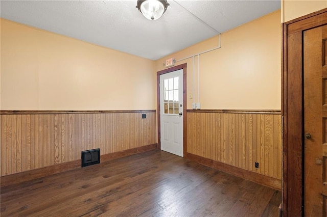 unfurnished room featuring dark hardwood / wood-style flooring and wood walls