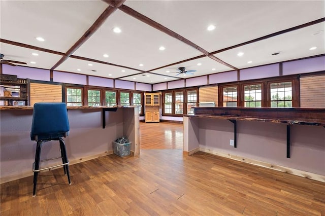 kitchen featuring light wood-type flooring, ceiling fan, and a breakfast bar area