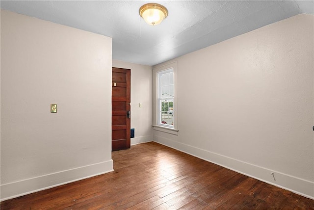 spare room with hardwood / wood-style floors and vaulted ceiling