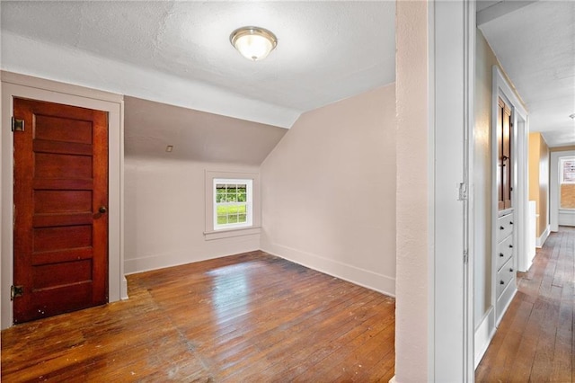 bonus room with a textured ceiling, vaulted ceiling, and hardwood / wood-style flooring