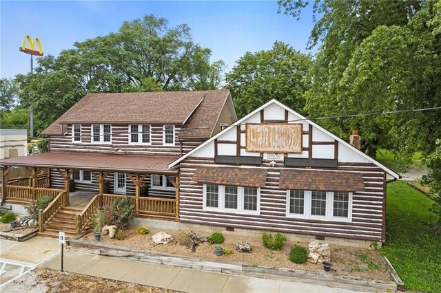 121 W US Highway 40, Odessa, MO 64076 - view of front facade featuring crawl space, log exterior, a chimney, and a shingled roof