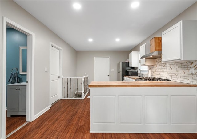 kitchen with backsplash, stainless steel appliances, dark hardwood / wood-style floors, white cabinets, and kitchen peninsula