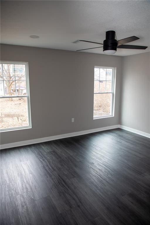 spare room featuring a wealth of natural light, dark hardwood / wood-style floors, and ceiling fan