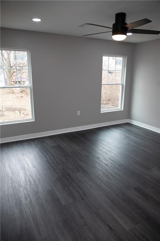 unfurnished room featuring ceiling fan, a wealth of natural light, and dark hardwood / wood-style flooring