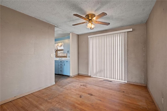 empty room with hardwood / wood-style floors, a textured ceiling, and sink