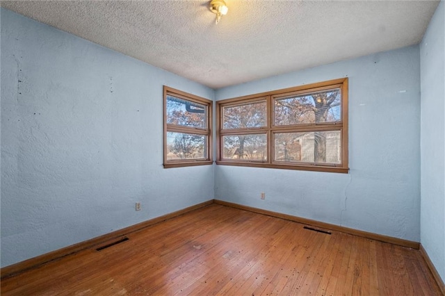 unfurnished room with wood-type flooring and a textured ceiling