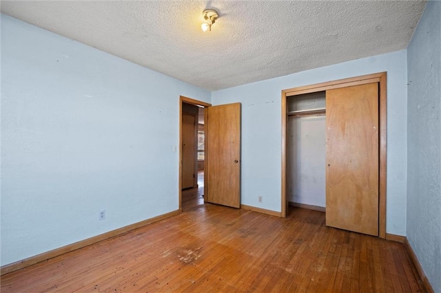 unfurnished bedroom featuring wood-type flooring, a textured ceiling, and a closet