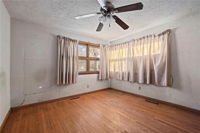 empty room featuring a textured ceiling, hardwood / wood-style flooring, and ceiling fan