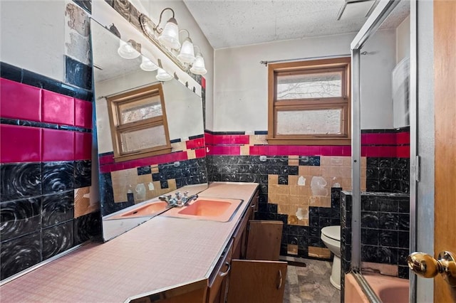 full bathroom featuring vanity, bath / shower combo with glass door, tile walls, and toilet