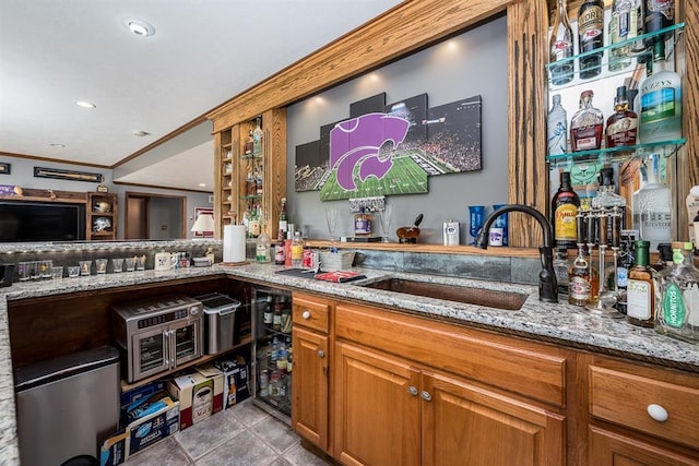 bar featuring light stone counters, ornamental molding, light tile patterned floors, and sink