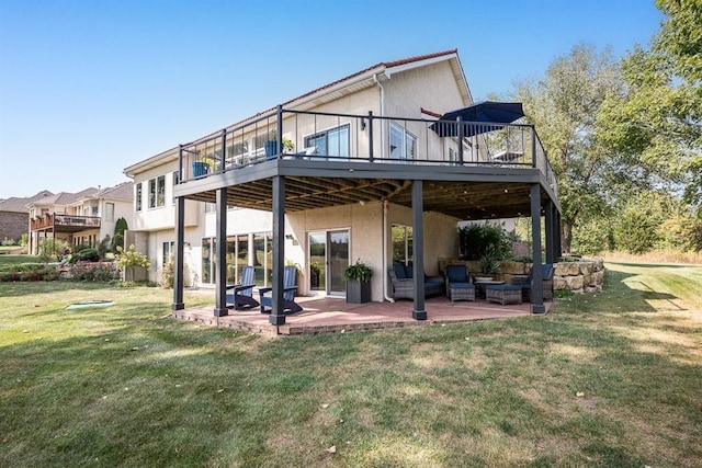 rear view of property featuring a patio, a deck, a lawn, and an outdoor living space