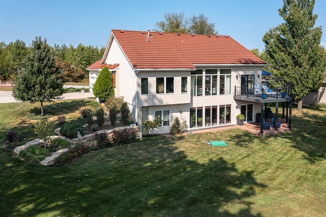 back of property featuring a patio, a wooden deck, and a lawn