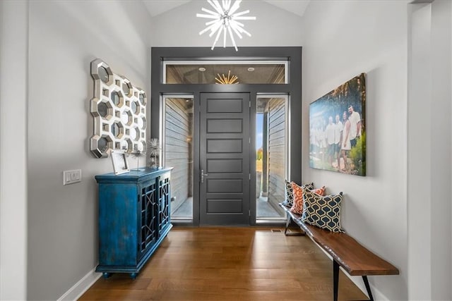 foyer with a chandelier, dark wood-type flooring, and lofted ceiling