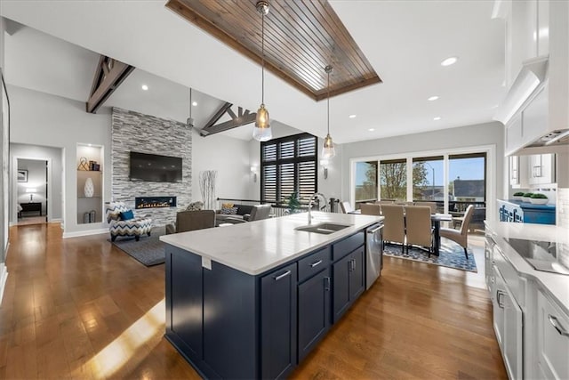 kitchen featuring pendant lighting, white cabinets, a center island with sink, sink, and dark hardwood / wood-style flooring