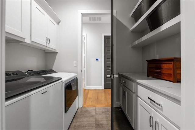 laundry area featuring cabinets, dark hardwood / wood-style floors, and independent washer and dryer