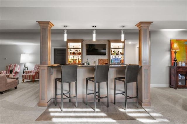 bar featuring pendant lighting, light colored carpet, and decorative columns