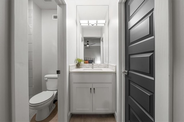 bathroom with ceiling fan, vanity, hardwood / wood-style flooring, and toilet