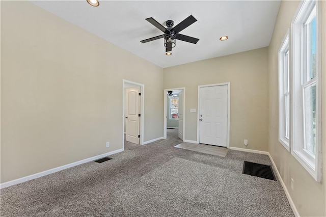 unfurnished room featuring a wealth of natural light, carpet floors, and ceiling fan