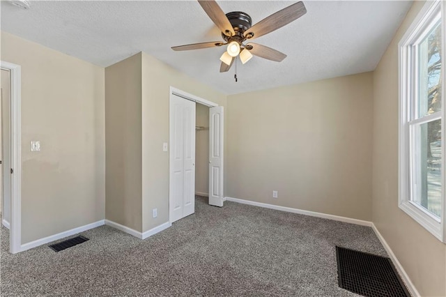 unfurnished bedroom with carpet flooring, multiple windows, ceiling fan, and a closet