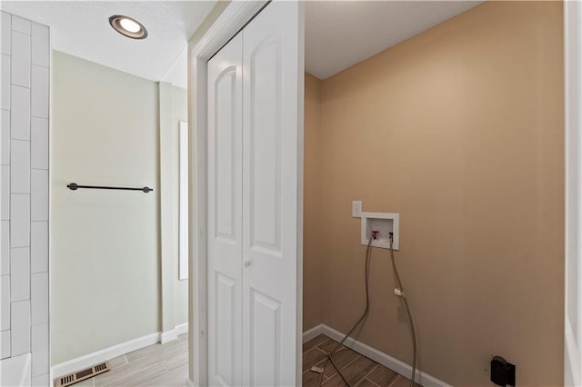 washroom with hookup for a washing machine, baseboards, visible vents, wood tiled floor, and laundry area