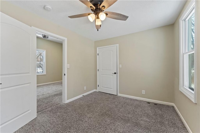 carpeted empty room with ceiling fan and baseboards