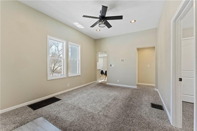 spare room with a ceiling fan, visible vents, carpet floors, and baseboards