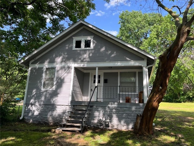 bungalow featuring covered porch and a front yard