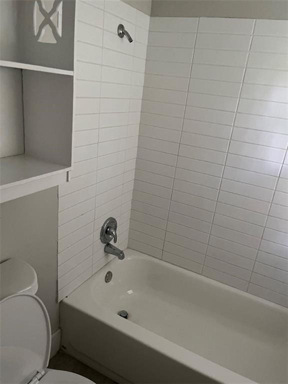 bathroom featuring tiled shower / bath combo and toilet