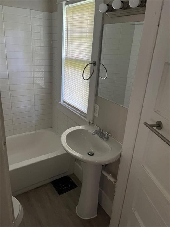 bathroom featuring hardwood / wood-style flooring, toilet, and tiled shower / bath