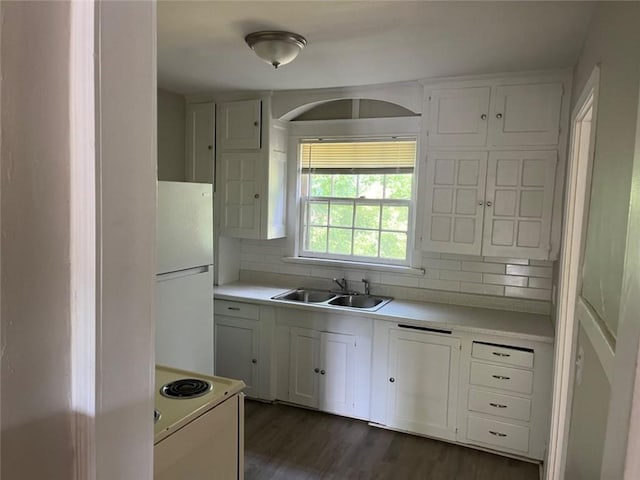 kitchen featuring white appliances, backsplash, white cabinetry, and sink