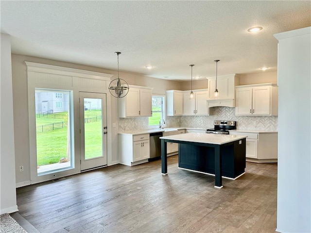 kitchen with a kitchen island, decorative light fixtures, white cabinetry, wood-type flooring, and stainless steel appliances