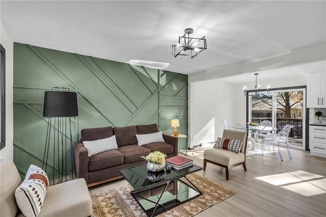 living room with light hardwood / wood-style flooring, a textured ceiling, and a notable chandelier