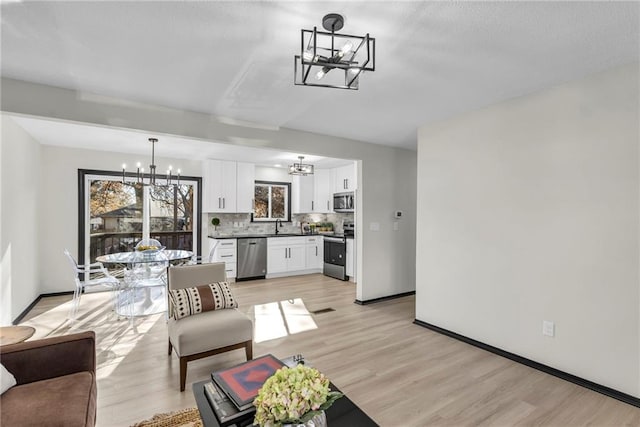 living room featuring light hardwood / wood-style floors, an inviting chandelier, and sink