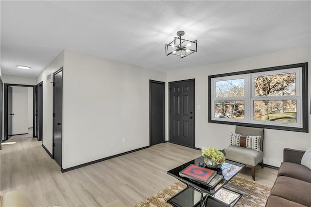 living room with light wood-type flooring and an inviting chandelier